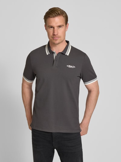 Männermodel trägt Regular Fit Poloshirt aus Baumwoll-Mix von s.Oliver RED LABEL, Optik: Unifarben, Label-Print, Piqué, Ganzkörperansicht von vorne.