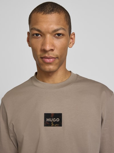 Männermodel trägt Regular Fit T-Shirt aus reiner Baumwolle Modell 'DUMEON' von HUGO in Unifarbe mit Label-Applikation, Nahaufnahme Oberkörper.