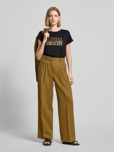 Frauenmodel trägt T-Shirt mit Rundhalsausschnitt und Print Modell 'MARICA' von Soyaconcept, Schwarz mit goldfarbenem Print, Relaxed Fit, Lyocell-Elasthan-Mix, kombiniert zu weiter Hose, Ganzkörperansicht von vorne.