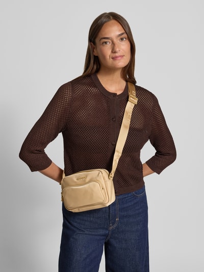 Frauenmodel trägt Umhängetasche mit Label-Detail Modell 'klosters neve lidia' von BOGNER in Beige, Hauptfach mit Reißverschluss, Nahaufnahme Oberkörper.