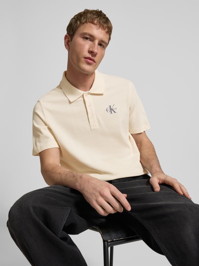 Männermodel trägt Easy Fit Poloshirt mit Polokragen von Calvin Klein Jeans, Reine Baumwolle, Label-Stitching, dezentes Beige, Nahaufnahme Oberkörper.