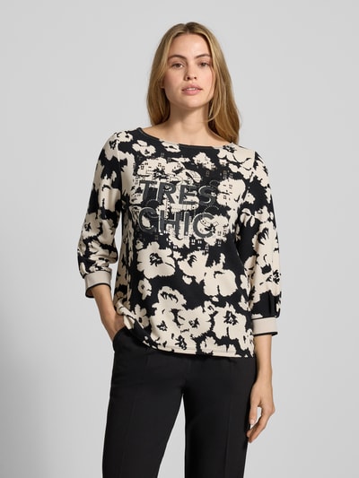 Frauenmodel trägt Sweatshirt aus Viskose-Mix mit 3/4-Arm von Betty Barclay, schwarz-beige Allover-Look, Statement-Print, Nahaufnahme Oberkörper.