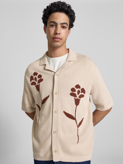 Männermodel trägt Relaxed Fit Freizeithemd aus reiner Baumwolle Modell 'SONNY' von Only & Sons in Strickoptik mit floralem Muster, beige Grundfarbe, durchgehende Knopfleiste, Resortkragen, Kurzarm, Ganzkörperansicht von vorne.