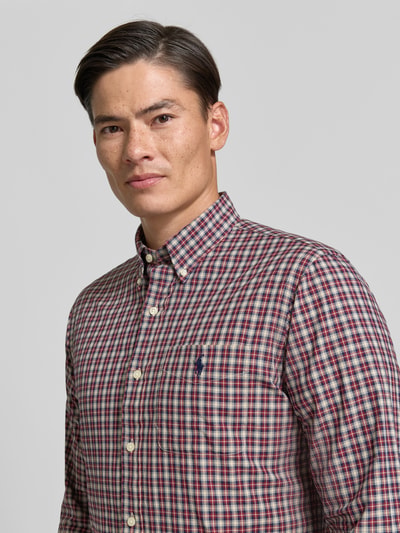 Männermodel trägt Custom Fit Freizeithemd aus reiner Baumwolle von Polo Ralph Lauren, kariertes Muster in Rot und Blau, Nahaufnahme Oberkörper.