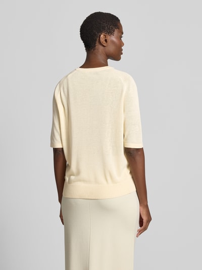 Frauenmodel trägt Strickshirt mit kurzer Knopfleiste Modell 'Turelia' von Someday, cremefarben, Material-Mix mit Lyocell-Anteil, Gerader-Schnitt, Rundhalsausschnitt, Raglanärmel, Rückenlänge bei Größe 36: 58 cm, Ärmellänge 24 cm, Ganzkörperansicht Rückansicht.