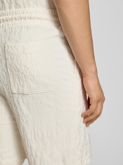 Männermodel trägt Regular Fit Shorts aus Frottee von HUGO in Frottee-Optik mit Logo-Stitching, seitlichen Eingrifftaschen, Nahaufnahme Rückansicht.