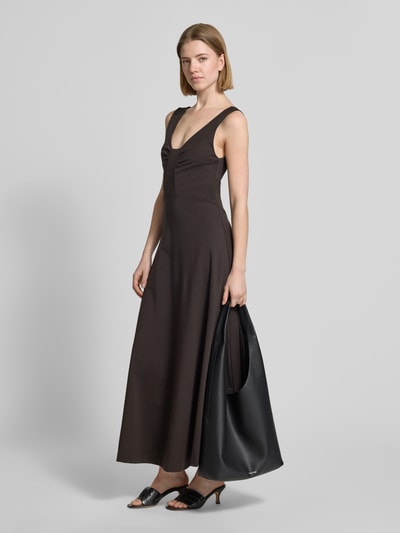 Frauenmodel trägt Maxikleid mit tiefem Rückenausschnitt Modell 'KLEALI' von Drykorn aus Lyocell-Mix mit Stretch-Anteil, taillierter Schnitt, V-Ausschnitt, breite Träger, dunkelbraune Farbe, glatte Textur, Ganzkörperansicht von vorne.