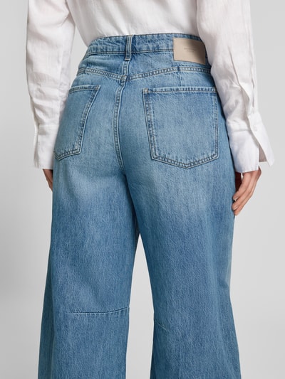 Frauenmodel trägt Barrel Fit Jeans mit Fransen von Rich & Royal aus reiner Baumwolle, Used-Look, blaue Waschung, Eingrifftaschen, Ganzkörperansicht Rückansicht.