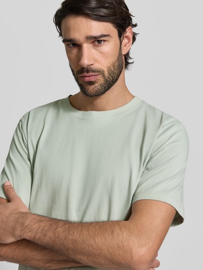 Męski model nosi Regular Fit T-Shirt aus reiner Baumwolle Modell 'ASPAN' od SELECTED HOMME, gładki jasny zielony dżersej, krótki rękaw, okrągły dekolt, materiał bawełniany, zbliżenie na górną część ciała.