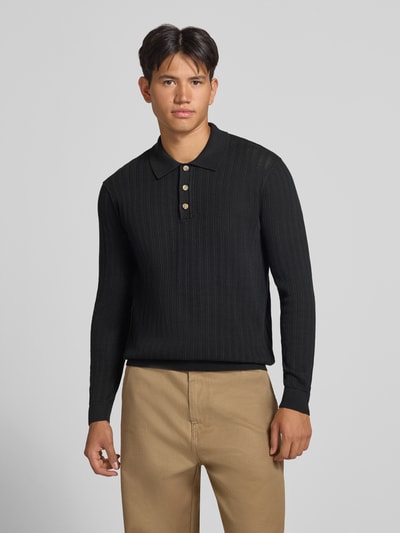 Männermodel trägt Regular Fit Poloshirt aus Baumwoll-Mix Modell 'MOON' von ONLY & SONS in Schwarz, Strukturmuster, Ganzkörperansicht von vorne.
