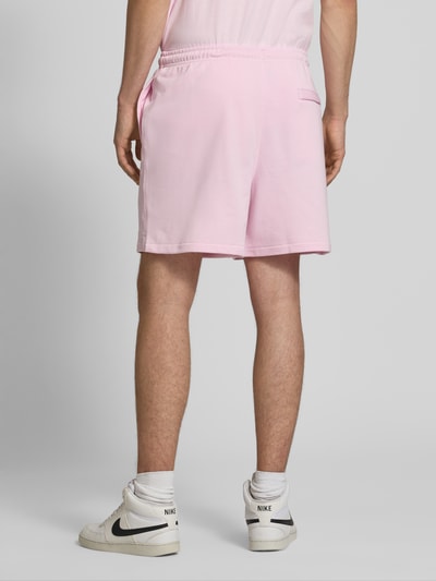 Männermodel trägt Shorts mit Label-Stitching und elastischem Bund von Nike aus Baumwoll-Mix in Rosa, Relaxed-Fit, Ganzkörperansicht Rückansicht.