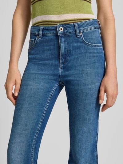 Kobieta nosi Flared Fit Jeans im 5-Pocket-Design Model 'Shelby' od Mustang z mieszanki bawełny, kolor niebieski, zapięcie na guzik i zamek błyskawiczny, szerokość w rozmiarze 27/32: 37 cm, długość wewnętrzna nogawki: 82 cm, zbliżenie na górną część ciała