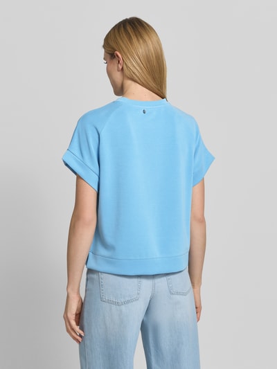 Modelka nosi Sweatshirt aus Modal-Mix mit Kappärmeln von Rich & Royal w kolorze jasnoniebieskim, krój relaxed fit, okrągły dekolt, krótkie rękawy, z dodatkiem streczu, widoczna gładka tekstura, widoczne przeszycia, widoczne spodnie z jasnego denimu, widok całej sylwetki z tyłu.
