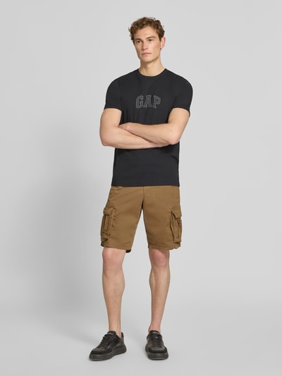 Männermodel trägt Straight Fit Shorts mit Cargo-Taschen Modell 'Core' von GAP in Braun aus Baumwoll-Mix mit Eingriffstaschen, Knopf- und Reißverschluss, Ganzkörperansicht von vorne.
