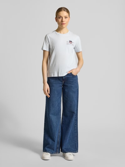 Frauenmodel trägt T-Shirt mit Rundhalsausschnitt und Label-Stitching von Gant aus Reine Baumwolle, Regular-Fit, Rückenlänge 57 cm, Ganzkörperansicht von vorne.