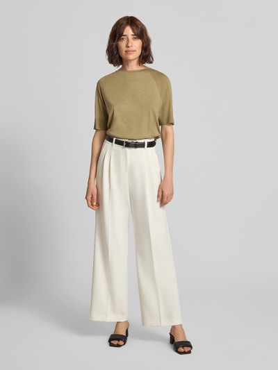 Frauenmodel trägt T-Shirt aus Lyocell-Baumwoll-Mix mit Rundhalsausschnitt von Luisa Cerano in Olivgrün, kombiniert mit weißen Stoffhosen, Regular Fit, feine Strickstruktur, Ärmel mit Rippenbündchen, Rückenlänge 60 cm, Ganzkörperansicht von vorne.