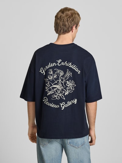 Männermodel trägt dunkelblaues T-Shirt mit Stitching und Rundhalsausschnitt von REVIEW, Oversized, reine Baumwolle, Rückenlänge 68 cm, Ganzkörperansicht Rückansicht.