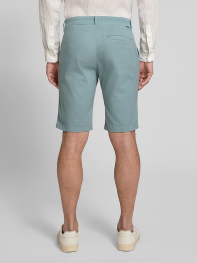 Männermodel trägt Slim Fit Chinoshorts aus reiner Baumwolle von Tom Tailor, Optik: Unifarben, Paspeltaschen, Ganzkörperansicht Rückansicht.