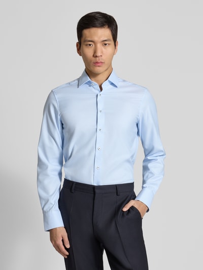 Männermodel trägt Slim Fit Business-Hemd mit Kentkragen von ETERNA, reine Baumwolle, Hellblau, Langärmelig, Knopfleiste, Ganzkörperansicht von vorne.
