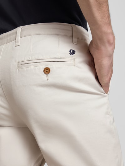 Mężczyznamodel nosi Regular Fit Shorts mit Münztasche od Superdry w kolorze jasnobeżowym, bawełniany materiał, tylne kieszenie, guzik i zamek, szerokość w rozmiarze 32: 44 cm, długość nogawki w rozmiarze 32: 20 cm, detal tylnej części, zbliżenie na kieszeń.