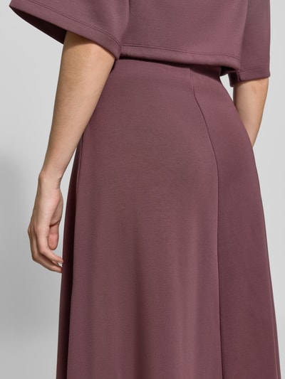 Vrouwenmodel draagt midirok met elastische band van Christian Berg Woman in mauve, elastische materiaalmix met modal, los model, midilengte, bandwijdte maat S 80 cm, detailopname heup- en taillezone.