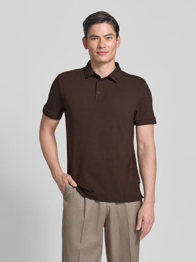Męski model nosi Regular Fit Poloshirt mit Knopfleiste Modell 'Carlosjuan' od JOOP! Collection, bawełniany miks ze stretchem, krój regular fit, kołnierzyk polo, krótka listwa guzikowa, długość pleców w rozmiarze M: 69 cm, widok całej sylwetki z przodu.