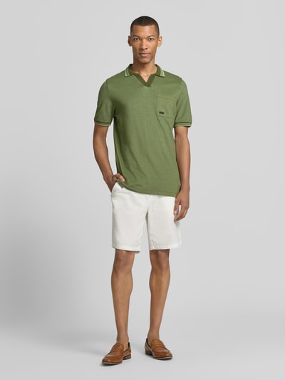 Männermodel trägt Regular Fit Poloshirt aus reiner Baumwolle Modell 'OPEN COLLAR POLO' von s.Oliver RED LABEL in Melange-Optik, Piqué-Struktur, grün, kurze Ärmel, Polokragen, Brusttasche, Label Stitching, Ganzkörperansicht von vorne.