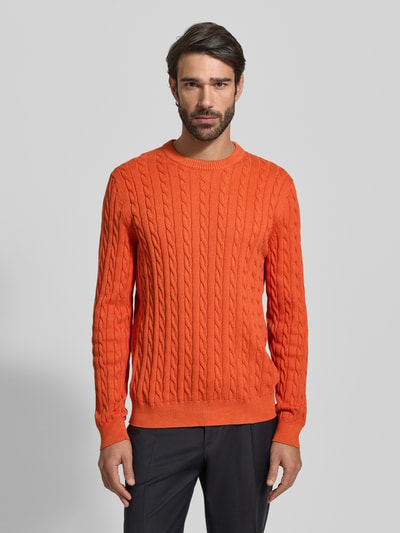 Männermodel trägt Strickpullover mit gerippten Abschlüssen von Christian Berg Men, reine Baumwolle, Regular-Fit, Rundhalsausschnitt, knalliges Orange, glatte Struktur, Ganzkörperansicht von vorne.