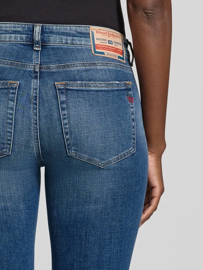 Frauenmodel trägt Flared Fit Skinny Jeans aus Baumwoll-Mix von Diesel, mittleres Blau mit leichter Waschung, 5-Pocket-Design, Nahaufnahme Rückansicht, Damen Skinny Jeans von Diesel, Baumwoll-Elasthan-Mix, Label-Detail, Knopf- und Reißverschluss, Bundweite 85 cm bei Größe 27, Innenbeinlänge 37 cm bei Größe 27