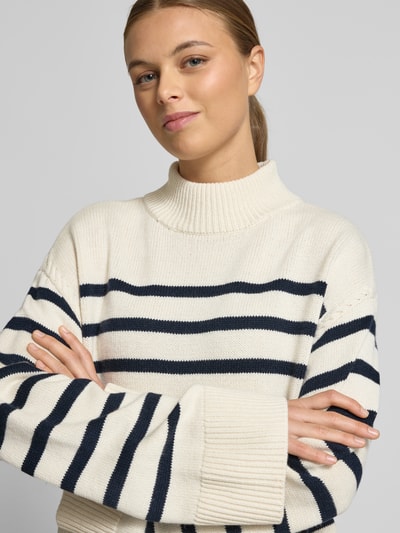 Frauenmodel trägt Regular Fit Pullover aus Woll-Mix Modell 'Sharad' von Lauren Ralph Lauren in Creme mit dunkelblauen Streifen, Stehkragen, breite Abschlüsse, Nahaufnahme Oberkörper.