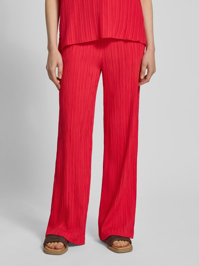 Frauenmodel trägt Hose mit Strukturmuster Modell 'Grsvalse' von FREE/QUENT in kräftigem Rot, Material-Mix, weites Bein, Nahaufnahme Unterkörper.