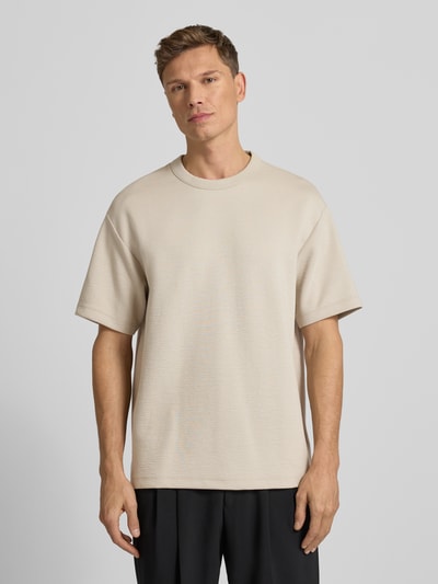 Männermodel trägt T-Shirt mit Rundhalsausschnitt Modell 'CRINKLE CREPE SPACER' von CK Calvin Klein, beige, Strukturmuster, Relaxed Fit, Ganzkörperansicht von vorne.