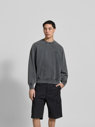 Männermodel trägt Oversized Hoodie aus Baumwoll-Mix von MAISON KITSUNÉ in Grau, Used-Look, elastische Abschlüsse, Ganzkörperansicht von vorne.