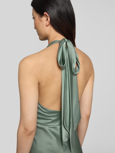 Kobieta modelka nosi Knielanges Cocktailkleid aus Satin od Hey Kyla, zielony satynowy materiał, bez rękawów, elastyczny materiał, widoczne marszczenia, detal wiązania na szyi, szerokość w rozmiarze 36: 38 cm, długość tyłu 97 cm, krój dopasowany, zdjęcie ukazujące górną część pleców z tyłu.