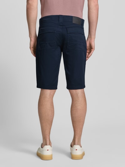 Mężczyzna nosi Regular Fit Cargoshorts aus Baumwoll-Mix od s.Oliver BLACK LABEL, granatowe, 5 kieszeni, bawełniany twill, etykieta z logo, widok całej sylwetki z tyłu.