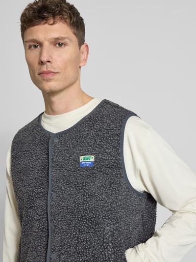 Männermodel trägt Straight fit bodywarmer met imitatiebont van model 'Hoktown' van American Vintage, logopatch, knoopsluiting, ronde hals, ruglengte maat M/L 64 cm, schouderbreedte 44 cm, borstwijdte 62 cm, Nahaufnahme Oberkörper.
