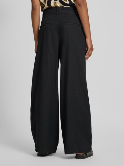 Frauenmodel trägt Wide Fit Stoffhose mit Bügelfalten Modell 'Livia' von Angels in Schwarz, Reine Baumwolle, Eingriff- und Gesäßtaschen, Ganzkörperansicht Rückansicht.