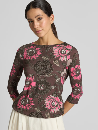 Modelka nosi T-Shirt im Allover-Look mit 3/4-Arm von Christian Berg Woman, damski t-shirt, mieszanka wiskozy i elastanu, krój slim fit, wzór na całej powierzchni, okrągły dekolt, rękaw o dł. 3/4, Długość tyłu w rozmiarze S: 55 cm, brązowy z różowymi i czarnymi kwiatami, miękka tekstura; zbliżenie górnej części ciała od przodu.