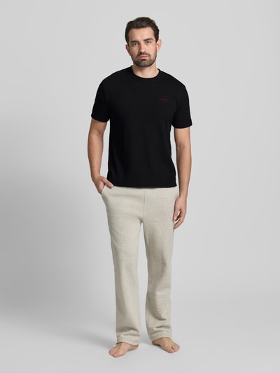 Mannenmodel draagt T-shirt met Label-Stitching model 'Austin' van HUGO in zwart, katoenmix, regular fit, voorkant volledige lichaamsweergave.