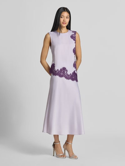 Frauenmodel trägt Top mit Spitzenbesatz Modell 'PELLA' von YAS in Flieder mit lila Spitze, asymmetrische Form, Regular Fit, Ganzkörperansicht von vorne.