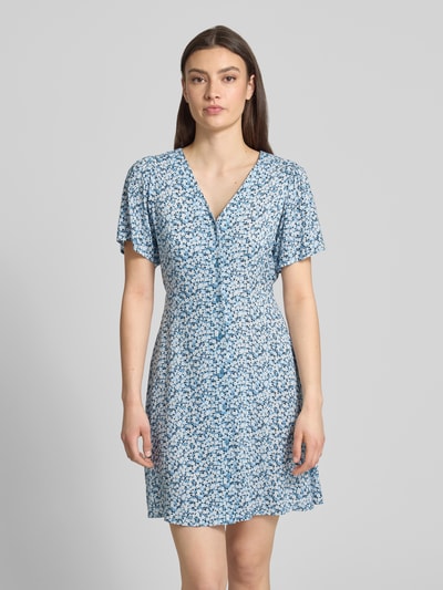 Frauenmodel trägt Minikleid aus reiner Viskose Modell 'EVIDA' von Only mit Allover-Muster, tailliert, V-Ausschnitt, Kurzarm, Knopfleiste, Gürtel, Ganzkörperansicht von vorne.
