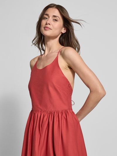 Kobiece modelka nosi sukienkę midi z wpuszczanymi kieszeniami model 'COVER' od SUNCOO PARIS, mieszanka bawełny, linia a, cienkie ramiączka, wiązanie z tyłu, długość tyłu w rozmiarze S: 114 cm, szerokość w rozmiarze S: 37 cm, ujęcie z przodu, zbliżenie na górę sylwetki.