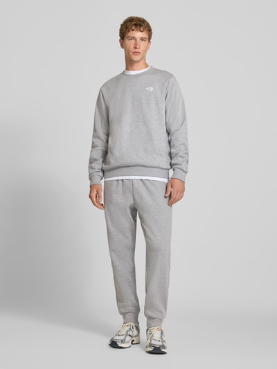 Mannenmodel draagt Regular Fit Sweatshirt Model "EVOLUTION" van The North Face, katoenmix, grijs, gestikt logo, elastische boorden, ronde hals, ruglengte maat M 67 cm, mouwlengte maat M 69 cm, full body frontale aanzicht.