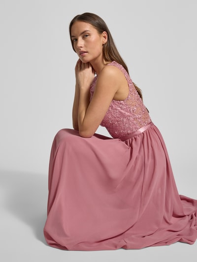 Modelka kobieca nosi różowe Abendkleid mit Paillettenbesatz od LUXUAR FASHION o taliowanym kroju, bez rękawów, widoczny połysk, zbliżenie na górną część sukienki, ujęcie z boku.