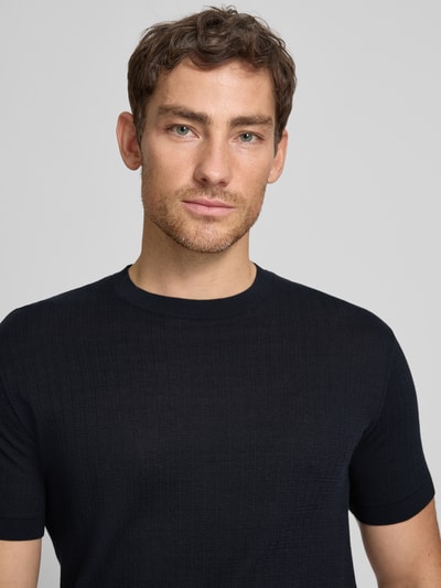 Mannenmodel draagt gebreid shirt met ronde hals van ARMANI EXCHANGE, puur katoen, slim fit, ruglengte bij maat M 69 cm, detailopname bovenlichaam.