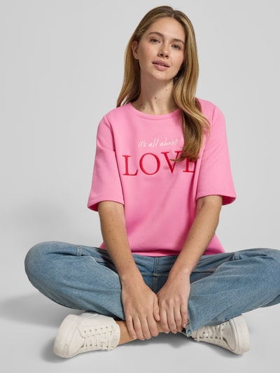 Frauenmodel trägt T-Shirt mit Statement-Stitching von Milano Italy in Pink mit Rundhalsausschnitt, Relaxed-Fit und Baumwoll-Mix, Ganzkörperansicht von vorne.