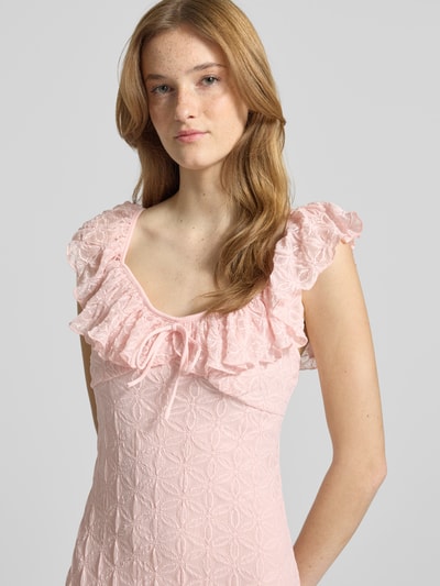 Frauenmodel trägt Midikleid mit Spitze und Schleifen-Detail von Gina Tricot in Rosa, enganliegend, strukturierter Material-Mix, Nahaufnahme Oberkörper.