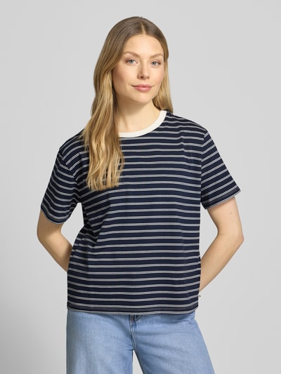 Modelka nosi damski t-shirt Boxy Fit T-Shirt aus reiner Baumwolle von Tom Tailor Denim, w paski, naszywka z logo, okrągły dekolt, krótki rękaw, drobne prążkowanie, 100% bawełna, widok całej sylwetki z przodu.