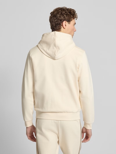 Männermodel trägt Regular Fit Sweatjacke aus reiner Baumwolle von Lacoste in Unifarben, Kapuze, Kontraststreifen, Ganzkörperansicht Rückansicht.