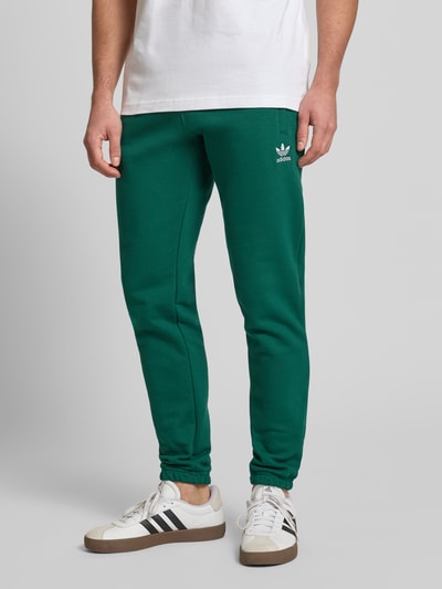 Männermodel trägt Sweatpants mit elastischem Bund von adidas Originals in Grün, Baumwoll-Mix, lockerer Schnitt, Nahaufnahme Unterkörper.